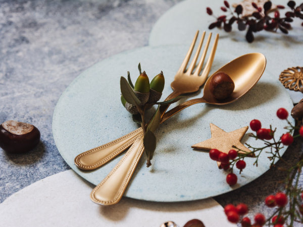 A plate and gold fork and knife with twigs and berries 